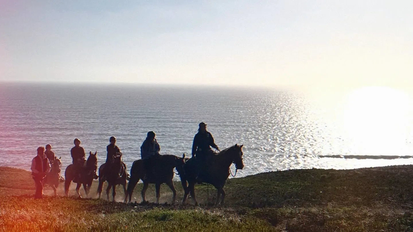 Riders on horseback silhouetted against the Pacific at sunset on the Daly City bluffs